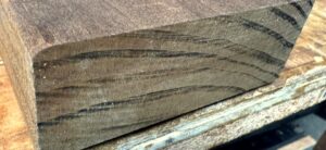 The cut end of a Kebony board, brown right through to the core