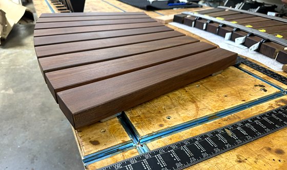 A curved Ipe seat section on the bench, mid-build, with a square alongside