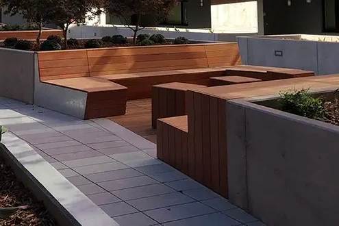 Custom Jatoba wood benches built into concrete planter walls in a residential courtyard